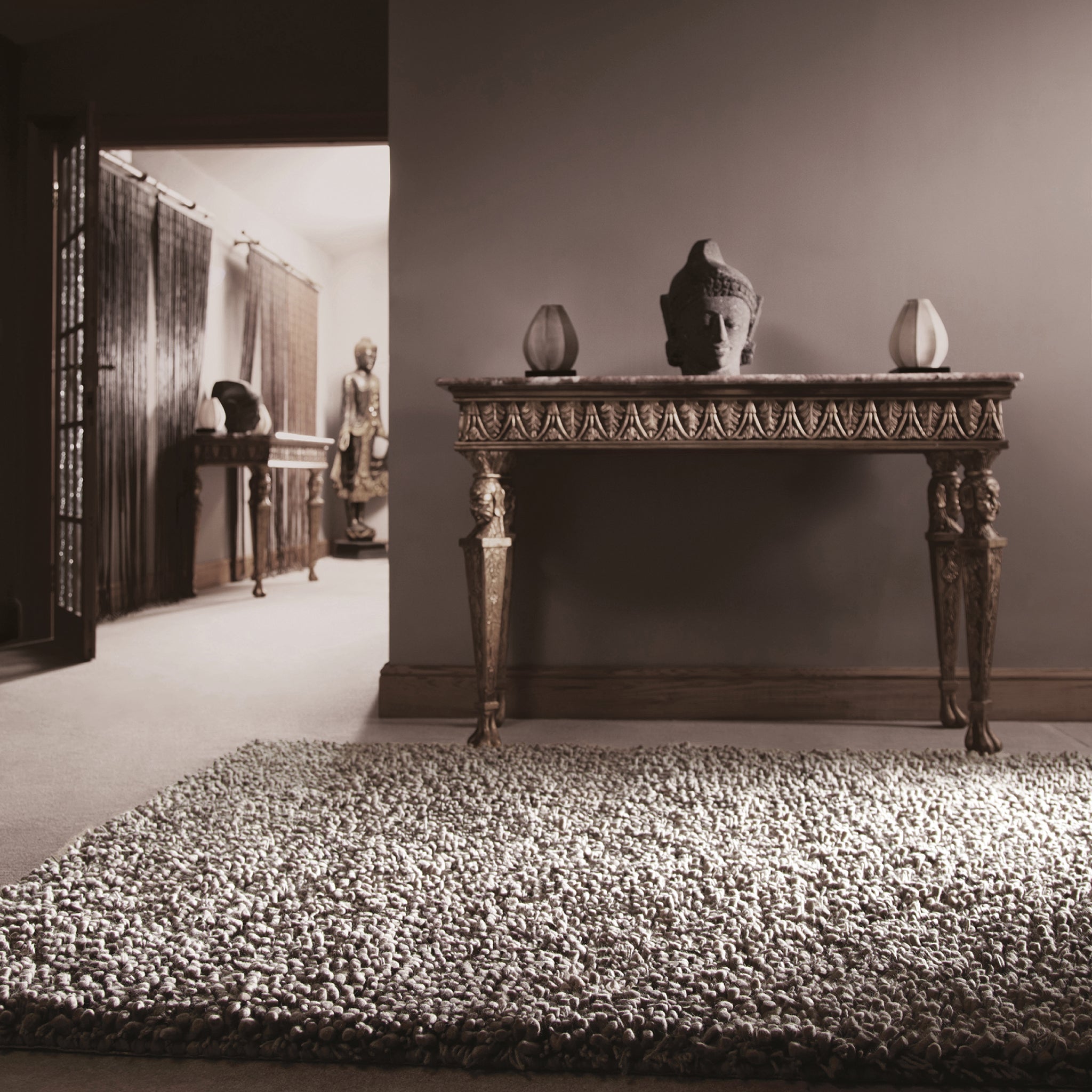 A dove grey hand-woven wool rug styled in a living room, showing scale against the furniture