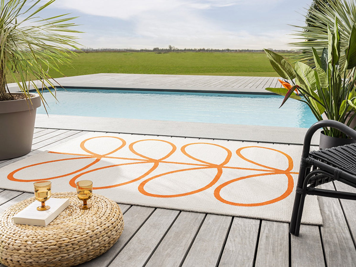 Orla Kiely Giant Linear Stem Persimmon outdoor rug on a terrace