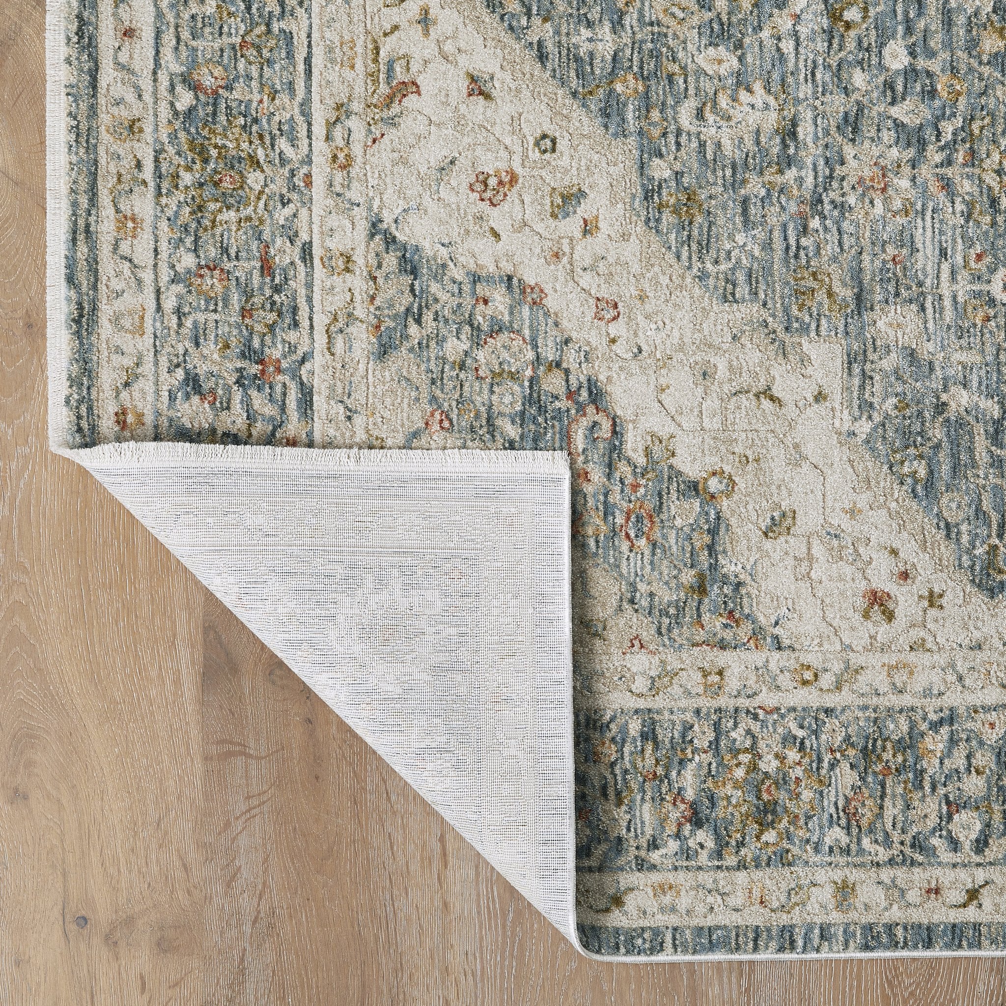 Comila Light Blue rug corner folded showing backing