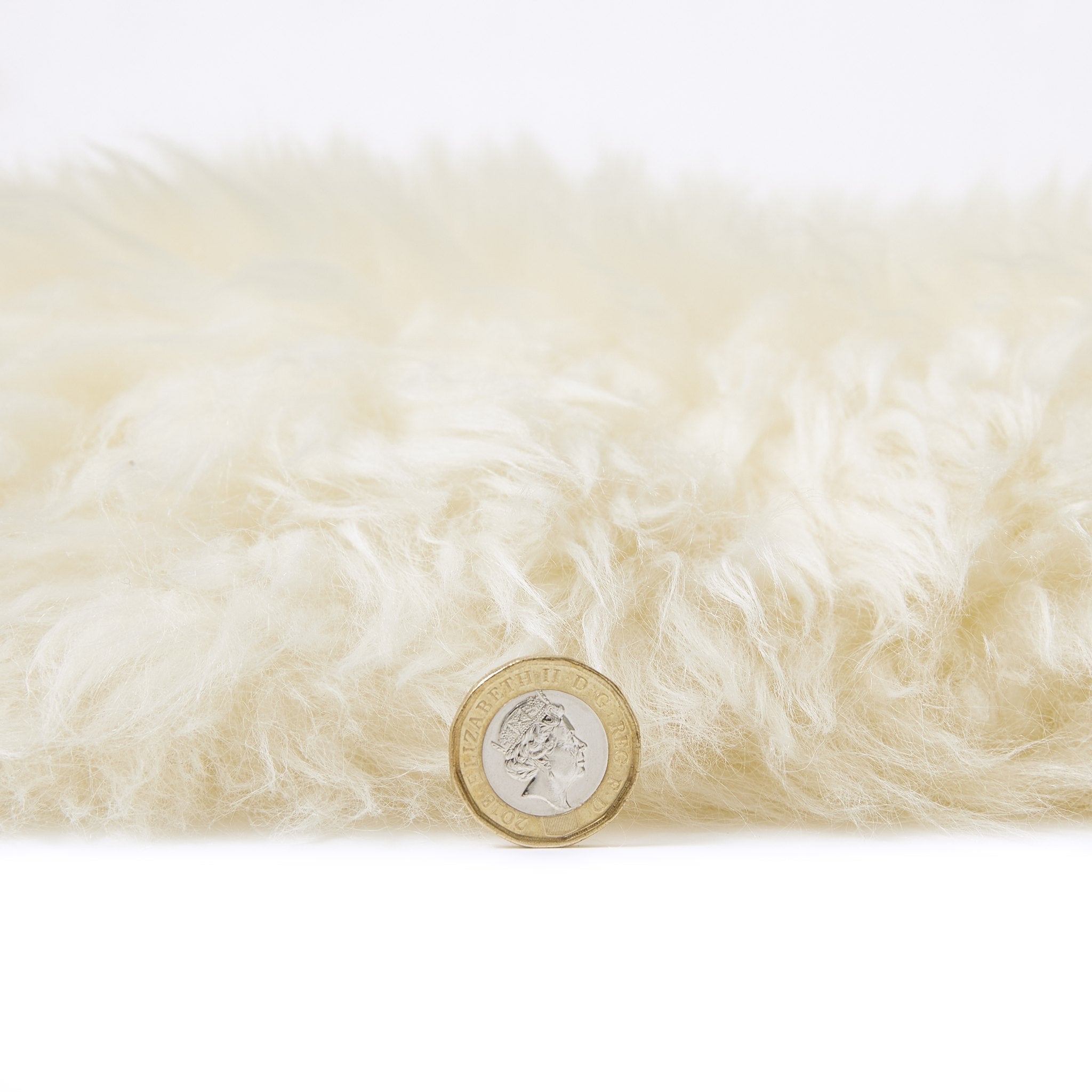 Faux Sheepskin Ivory rug pile height shown against a coin for scale