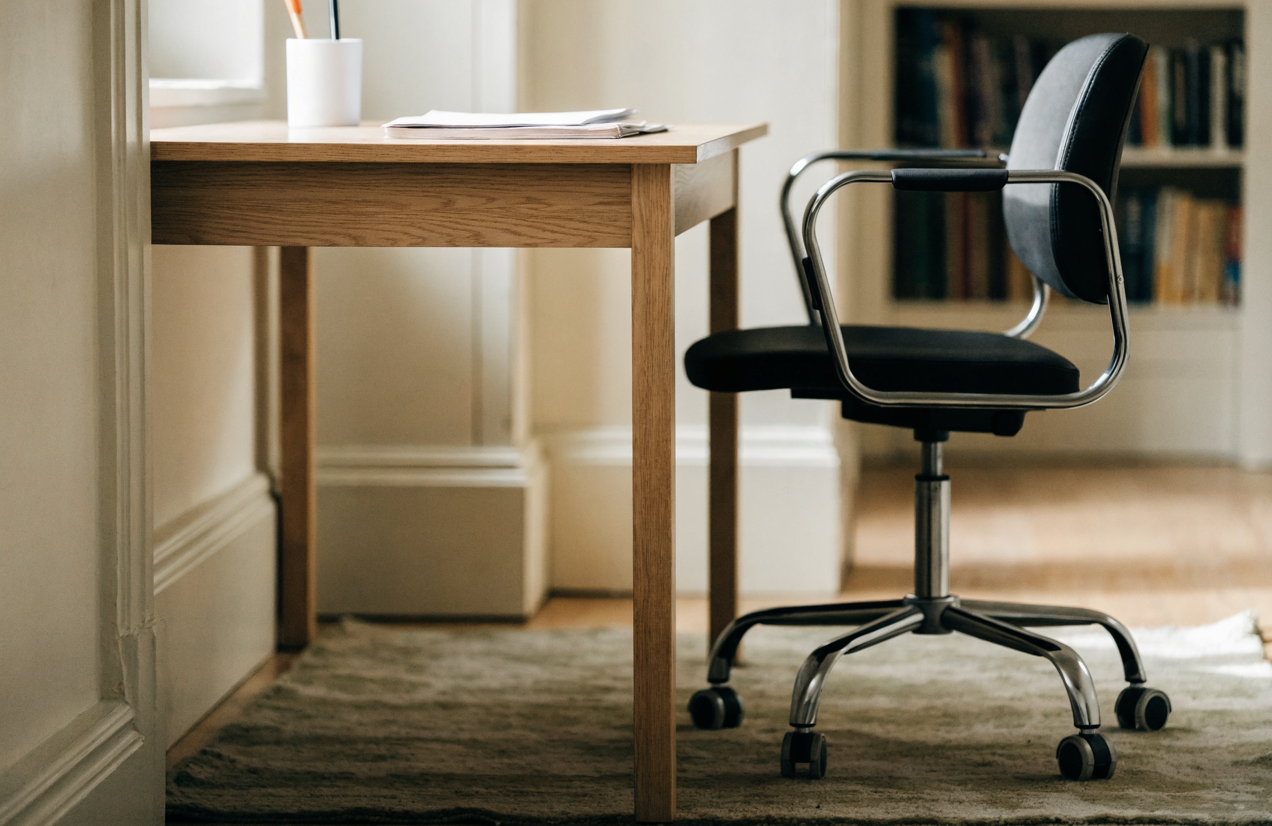 A low-pile flatweave rug beneath a desk and a task chair on castors in a home office