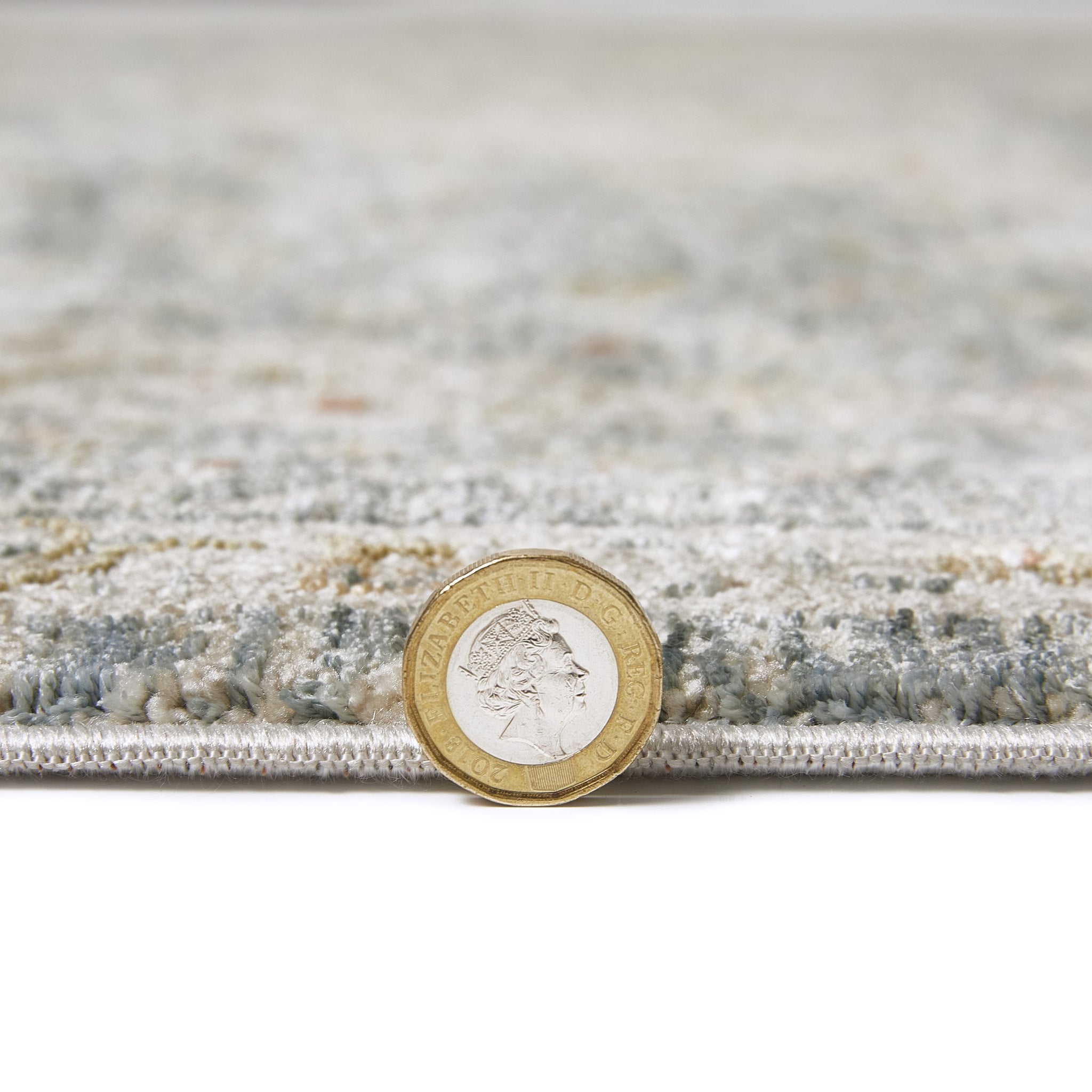 Comila Light Blue rug pile height shown against a coin for scale