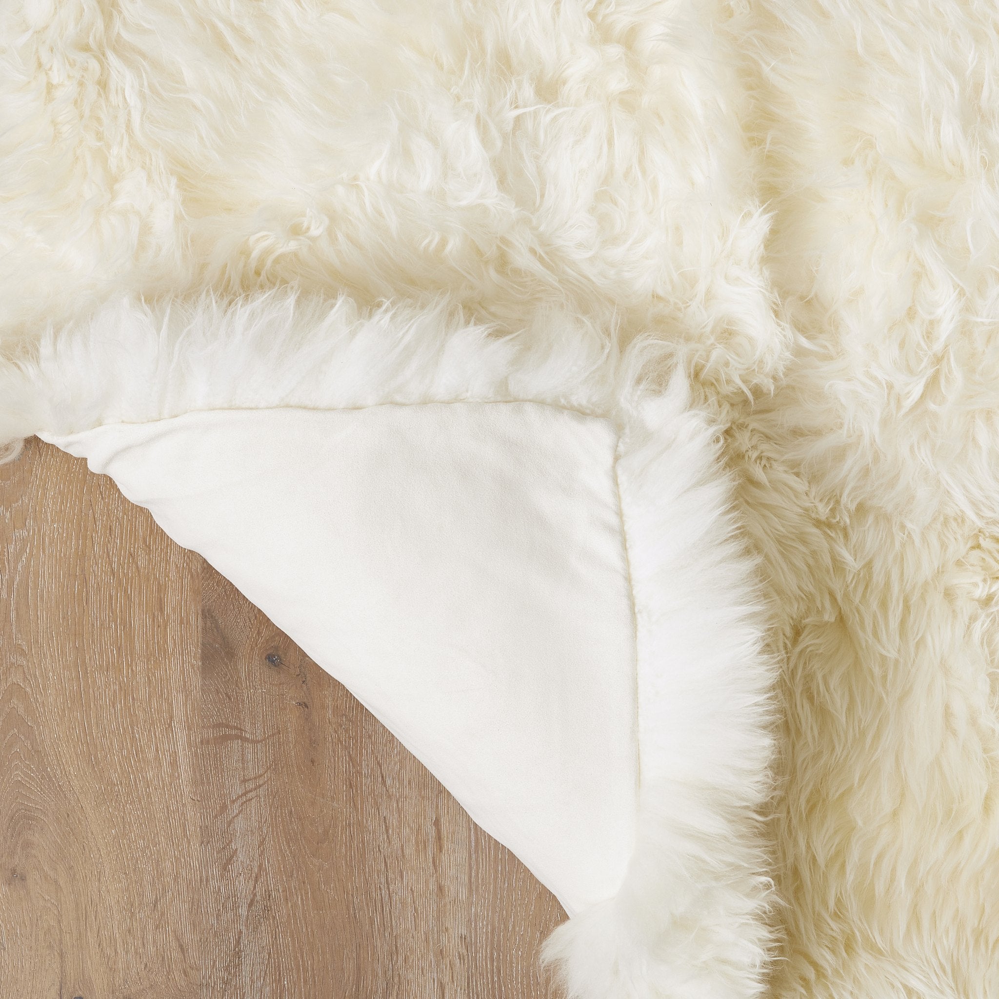 Faux Sheepskin Ivory rug corner folded showing suede backing
